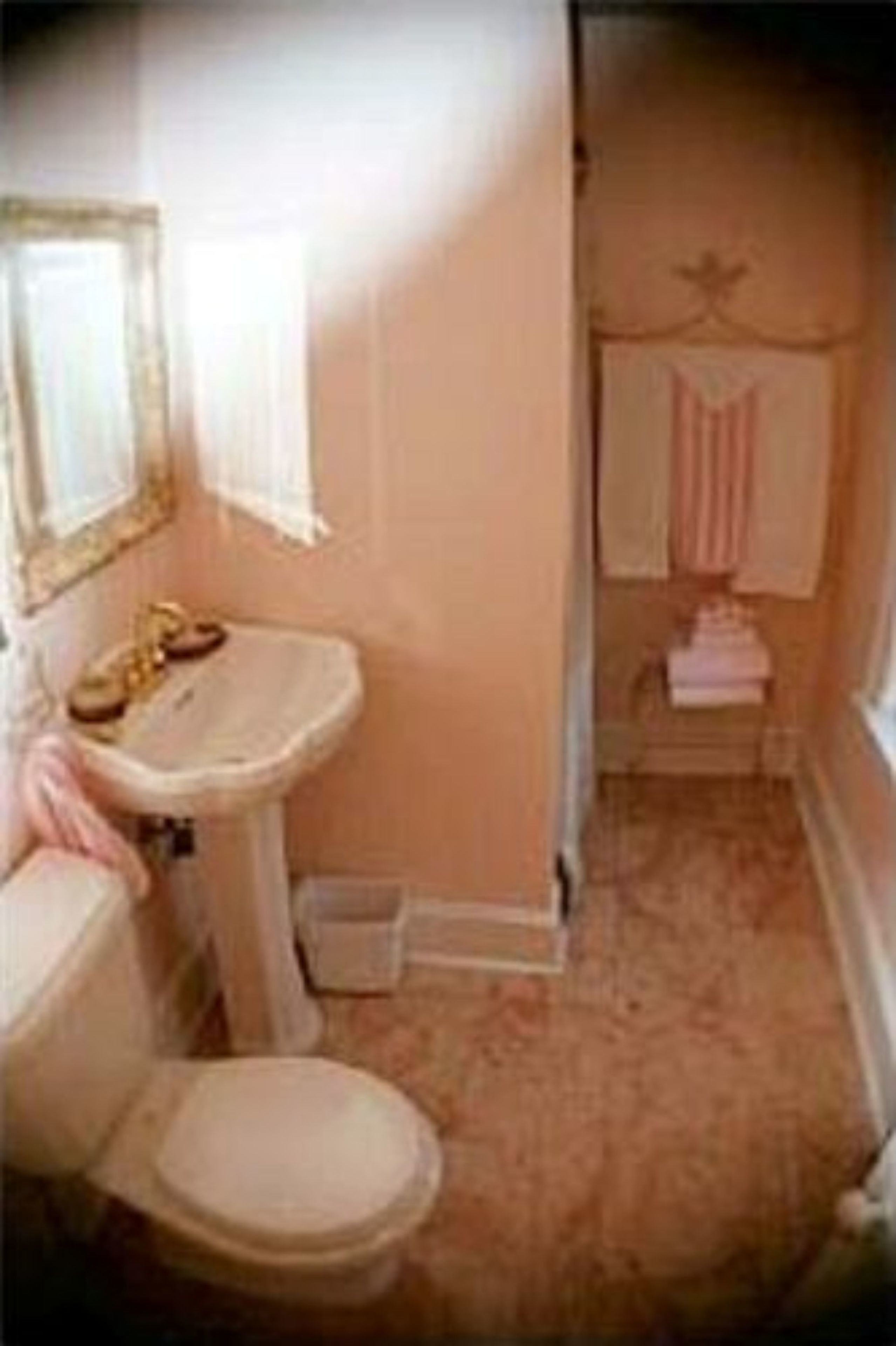 A bathroom with a toilet, sink, and mirror.