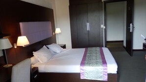 A hotel room with a large bed, two bedside lamps, a dark headboard, and a wardrobe. - Hotel des Deputes (Yaoundé)