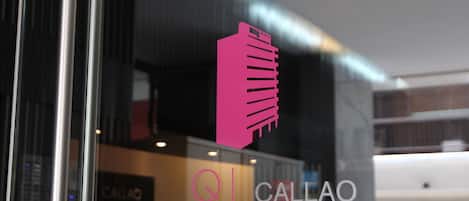 A modern building with a glass facade and a pink logo.