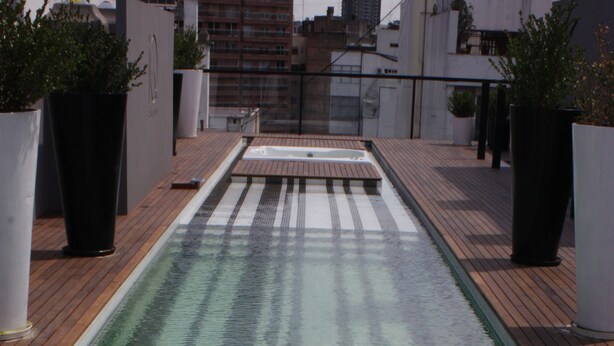 A rooftop pool with clear water, wooden deck, and potted plants. - IQ Callao by Recoleta Apartments (Buenos Aires)