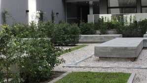 A modern building with a courtyard featuring a grassy area, concrete planters, and a gravel path. - IQ Callao by Recoleta Apartments (Buenos Aires)