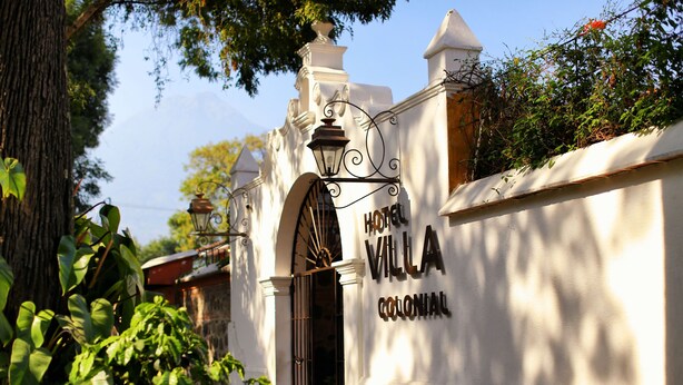 Hotel Villa Colonial with a colonial architectural style, featuring a large arched entrance and a signboard. - Villa Colonial (Antigua Guatemala)