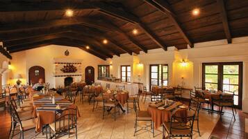 A spacious dining area with high wooden ceilings and multiple tables and chairs.