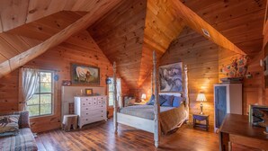 A cozy log cabin bedroom with a four-poster bed, a dresser, a small table, and a window with curtains. - Seventy-four Ranch (Jasper)
