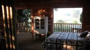 A cozy cabin interior with a bed, a small table, and a view of the outdoors. - Seventy-four Ranch (Jasper)