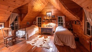 A cozy log cabin bedroom with two beds, a wooden ceiling, and a rustic ambiance. - Seventy-four Ranch (Jasper)