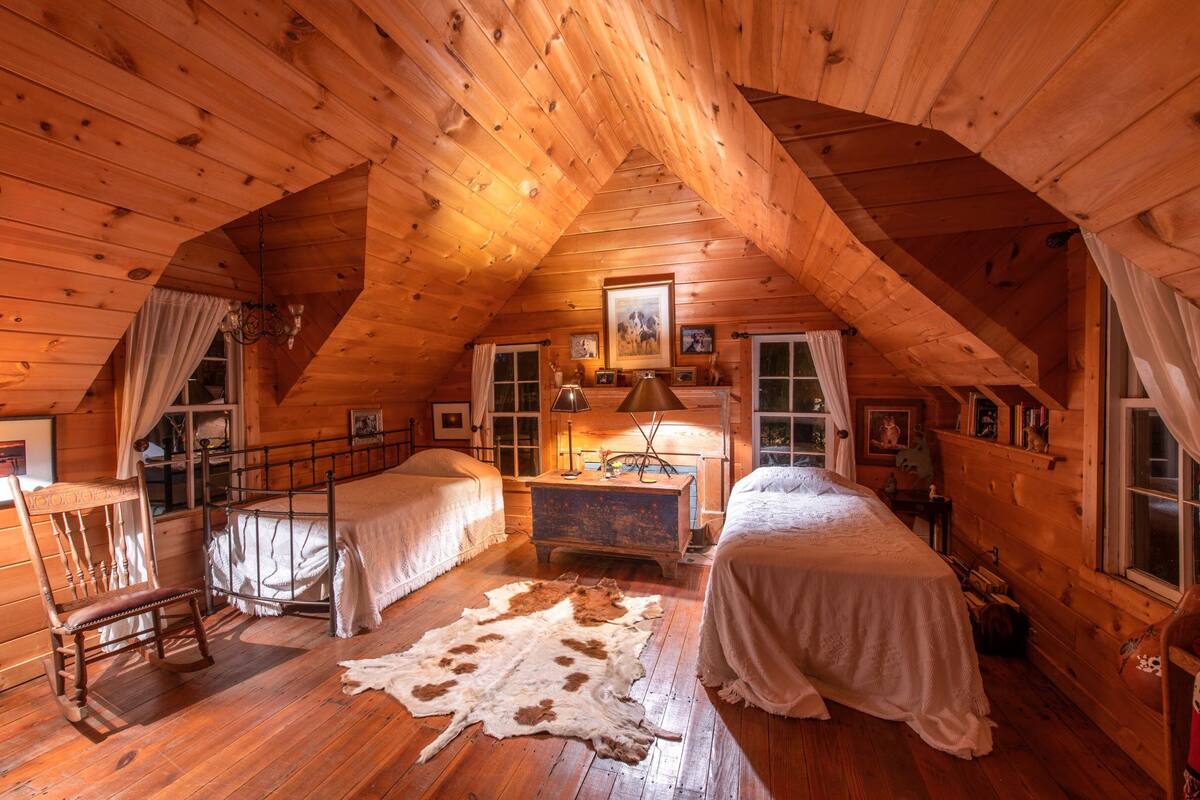 A cozy log cabin bedroom with two beds, a wooden ceiling, and a rustic ambiance.