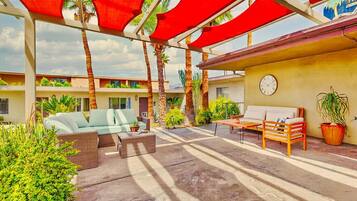 An outdoor patio area with a sofa, a wooden table, and a chair.