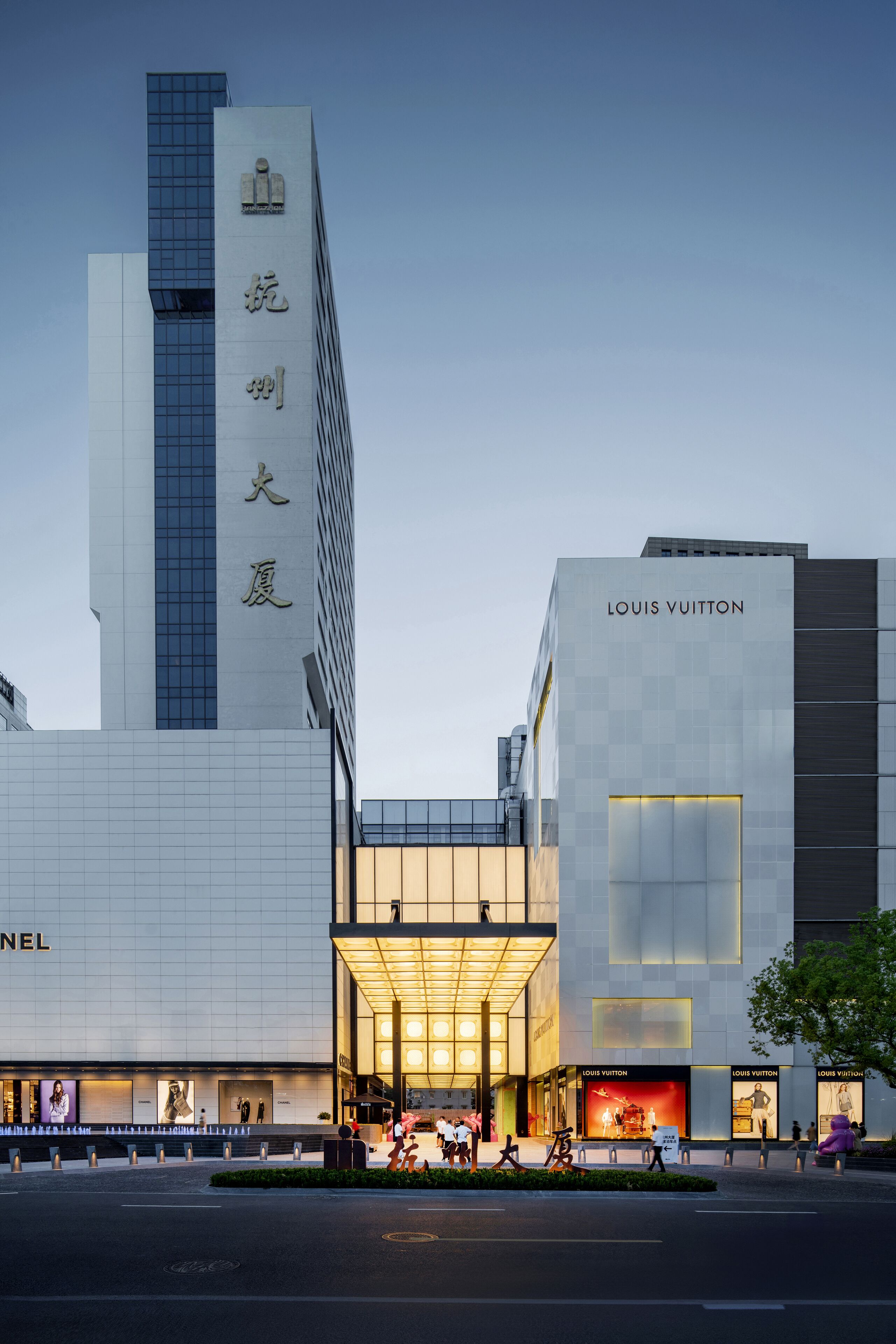 Ein modernes Gebäude mit einem markanten Louis Vuitton Geschäft, einem großen Eingangsbereich und einem sichtbaren Chanel Geschäft.