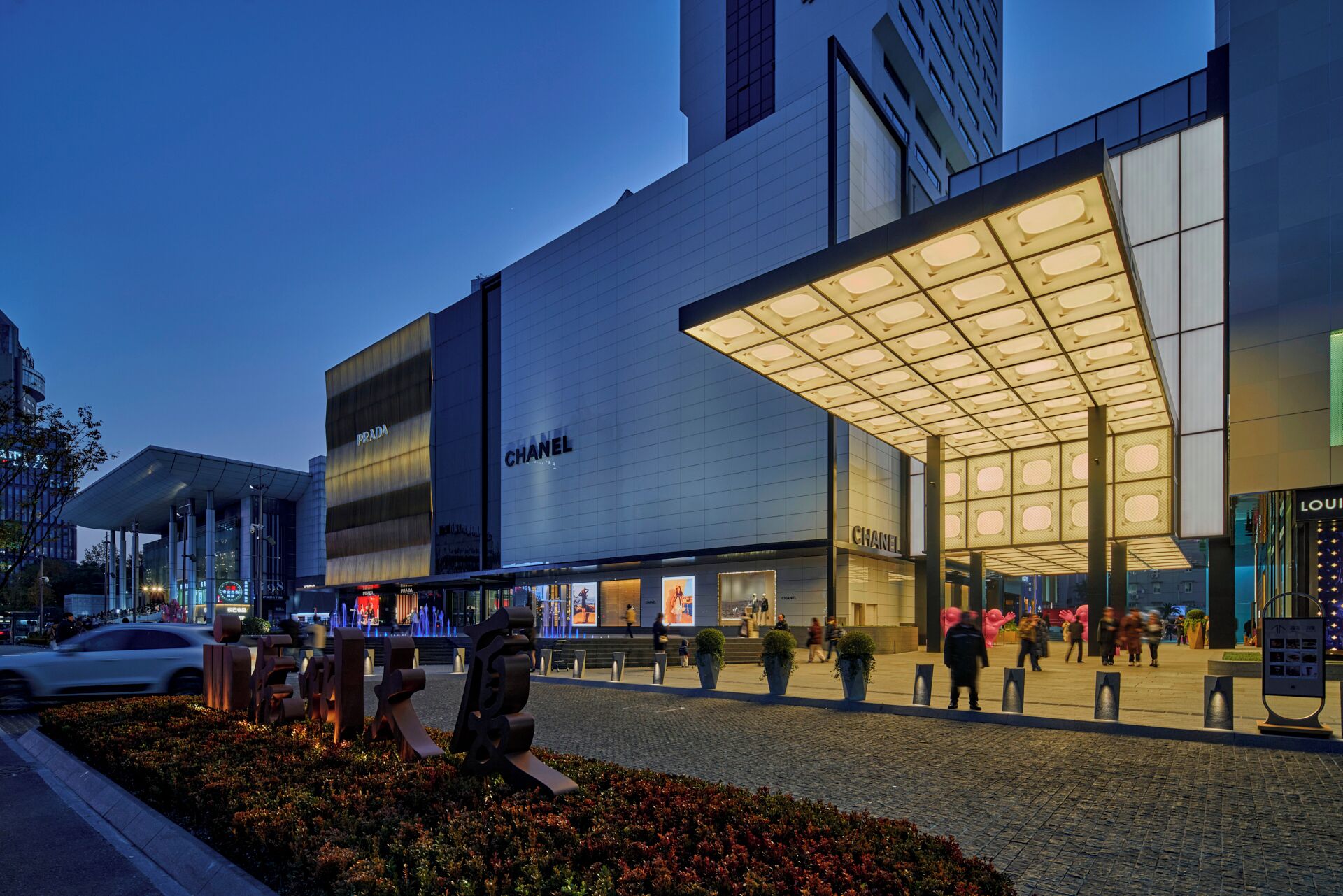 A modern building with prominent signage for Prada and Chanel.