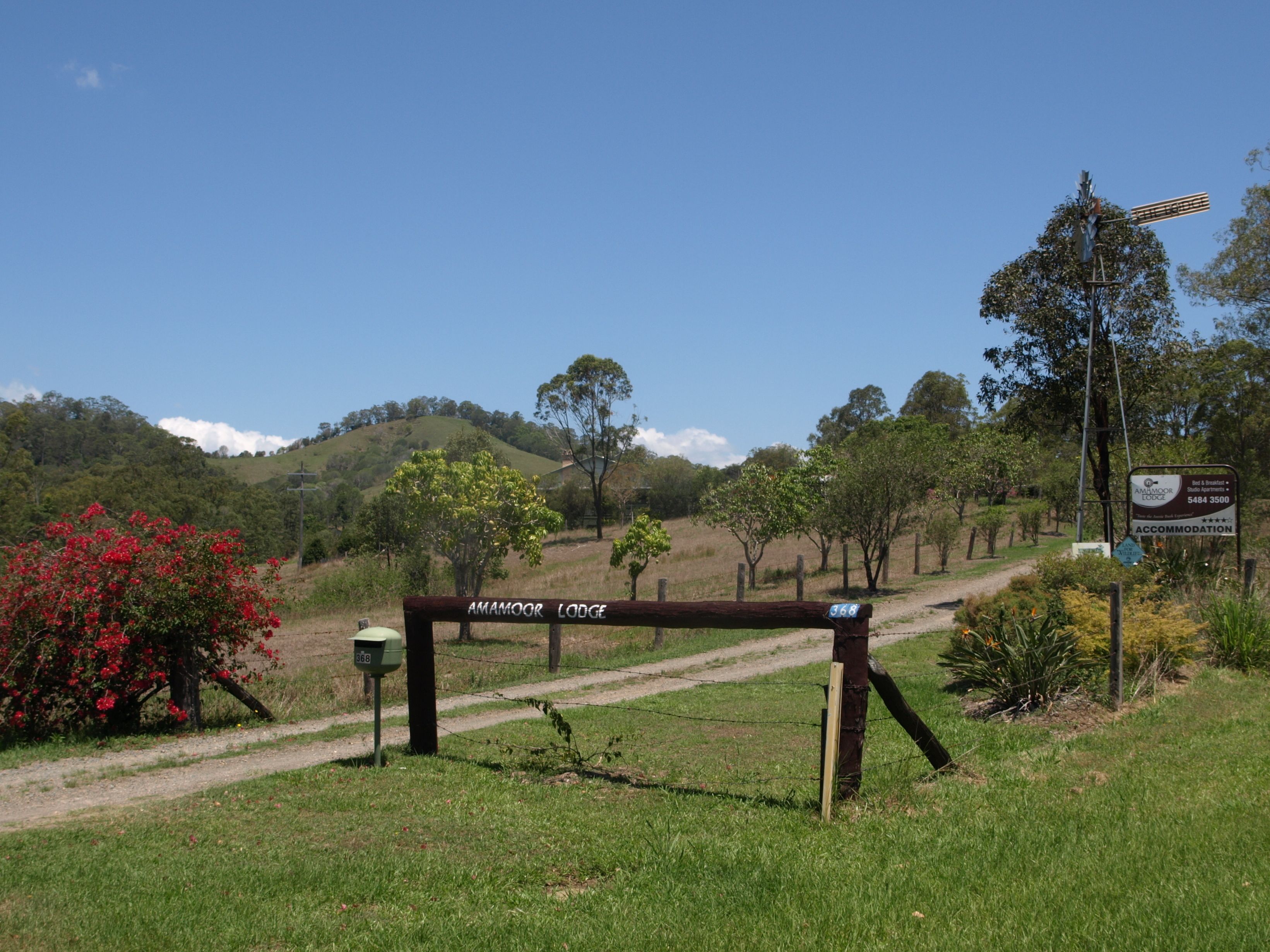 A sign for Amamoor Lodge with a dirt path leading to it.