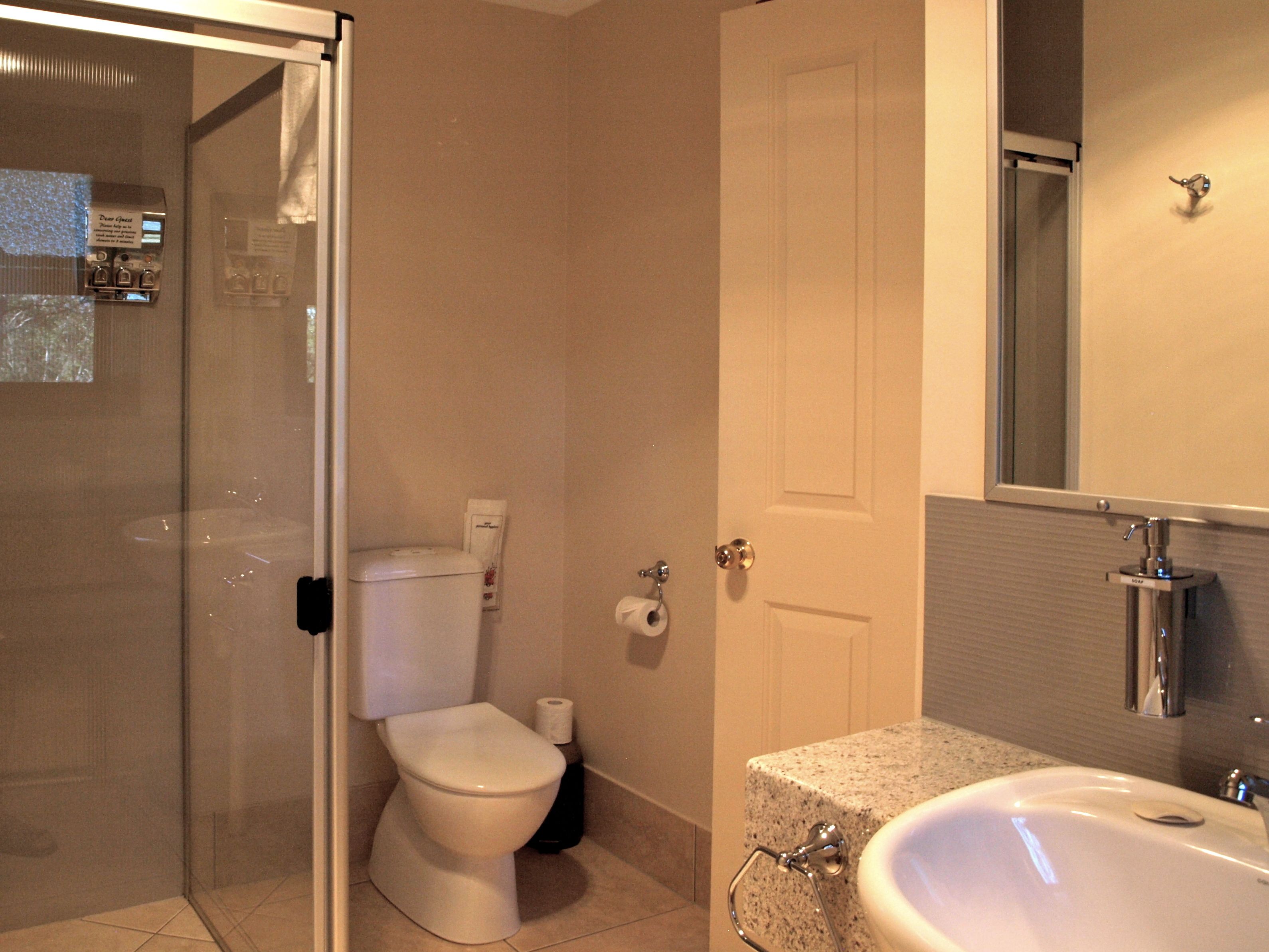 Een badkamer met toilet, douche en wastafel.