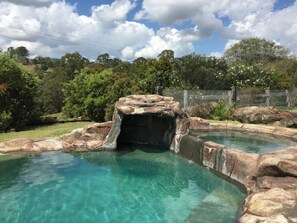 Una piscina al aire libre, sombrillas, sillones reclinables de piscina