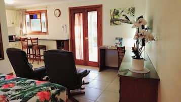 A compact room with a bed, a desk, a chair, and a small kitchenette.