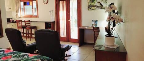 Une pièce de taille modeste comprenant un lit, un bureau, une chaise et une petite kitchenette.