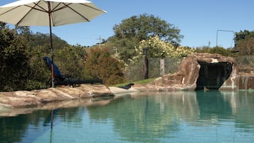 Alberca al aire libre, sombrillas en la alberca y camastros