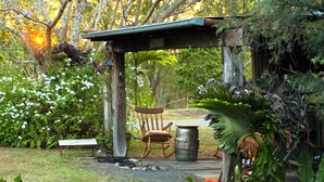 A garden with a wooden pergola, a rocking chair, and a barrel. - Amamoor Lodge (Amamoor)