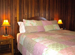 A bedroom with a wooden headboard, a quilted bedspread, two bedside lamps, and a nightstand with a lamp. - Amamoor Lodge (Amamoor)