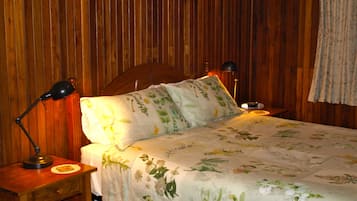 A wooden-paneled room with a bed, two bedside lamps, and a nightstand with a lamp.