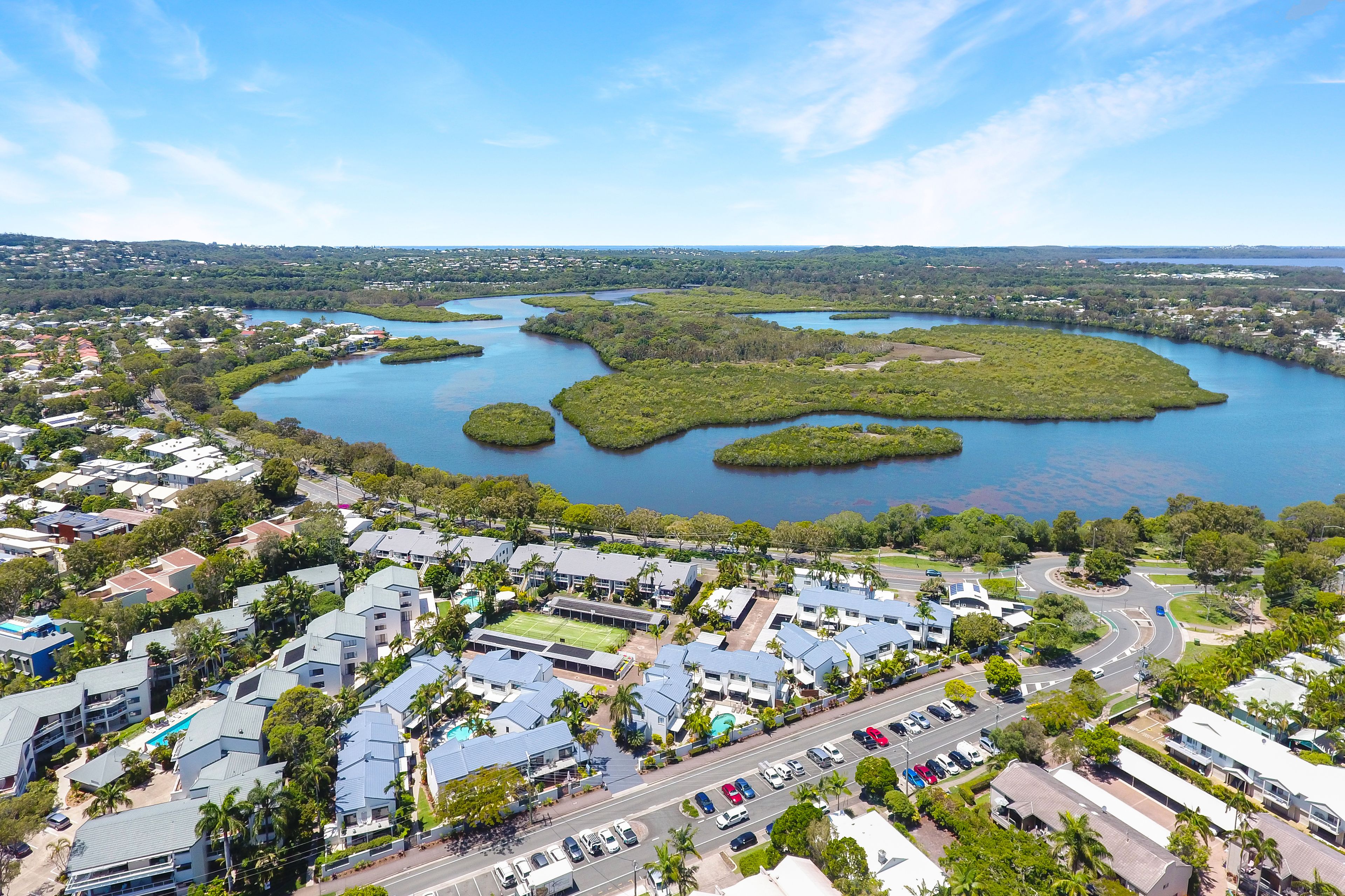 An aerial view of a coastal town with a marina, residential buildings, and a large body of water.