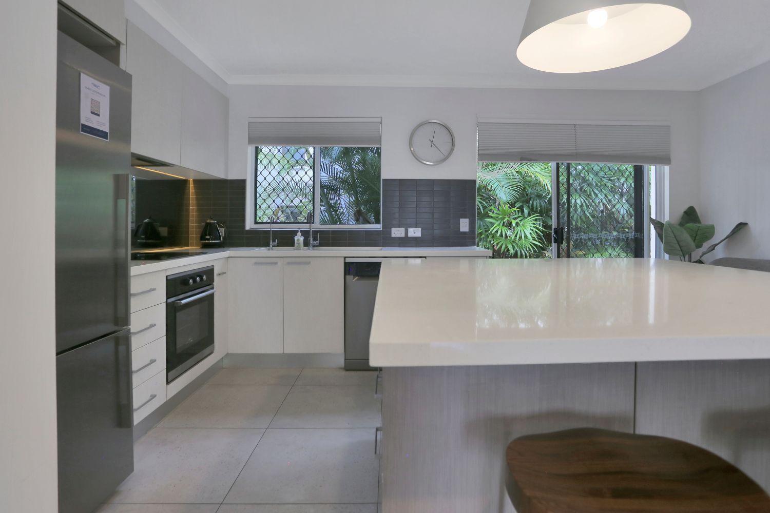 Una cocina moderna con una isla grande, electrodomésticos de acero inoxidable y vistas al exterior.