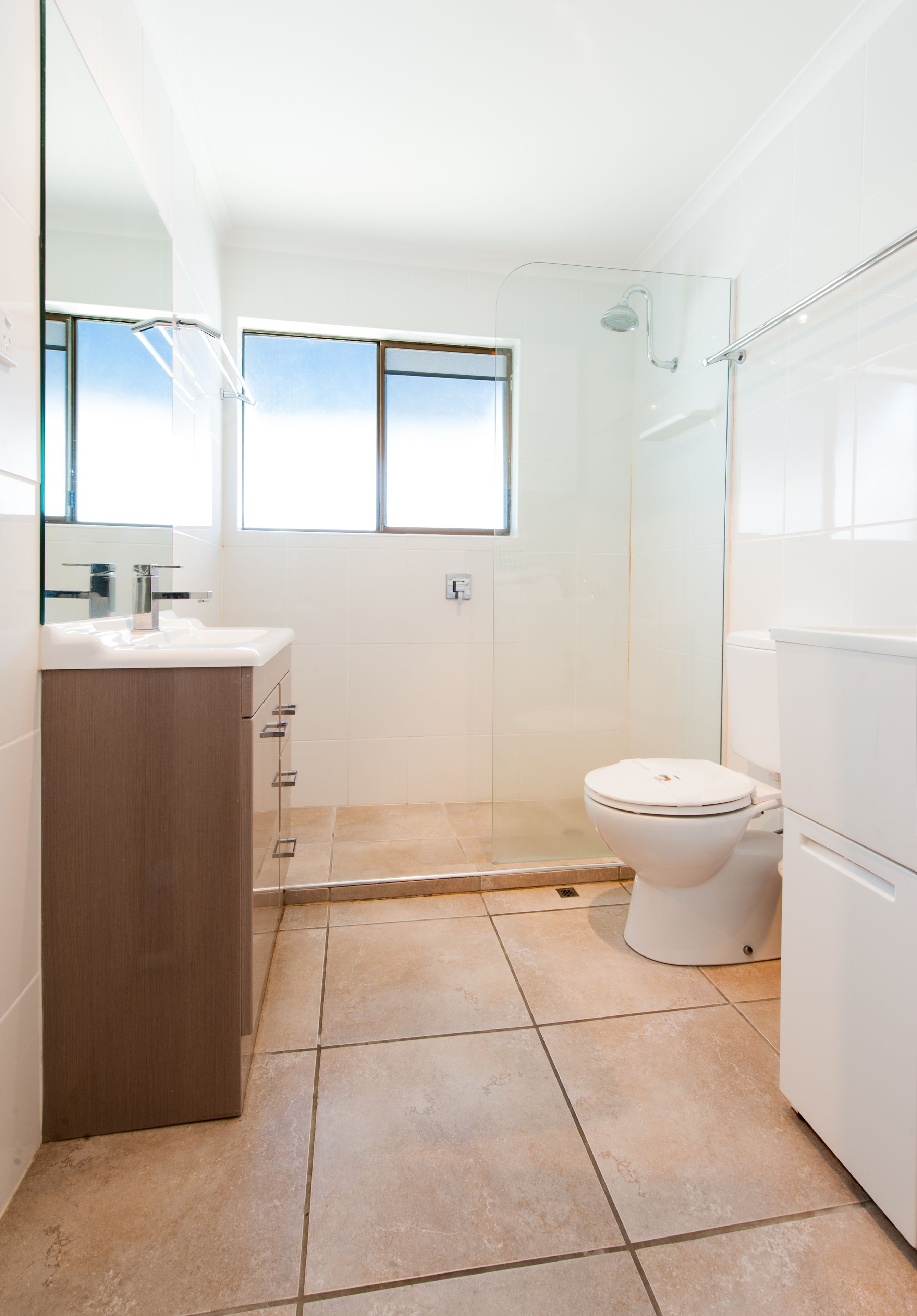 Un bagno moderno con box doccia in vetro, un WC bianco e un mobile bagno in legno.
