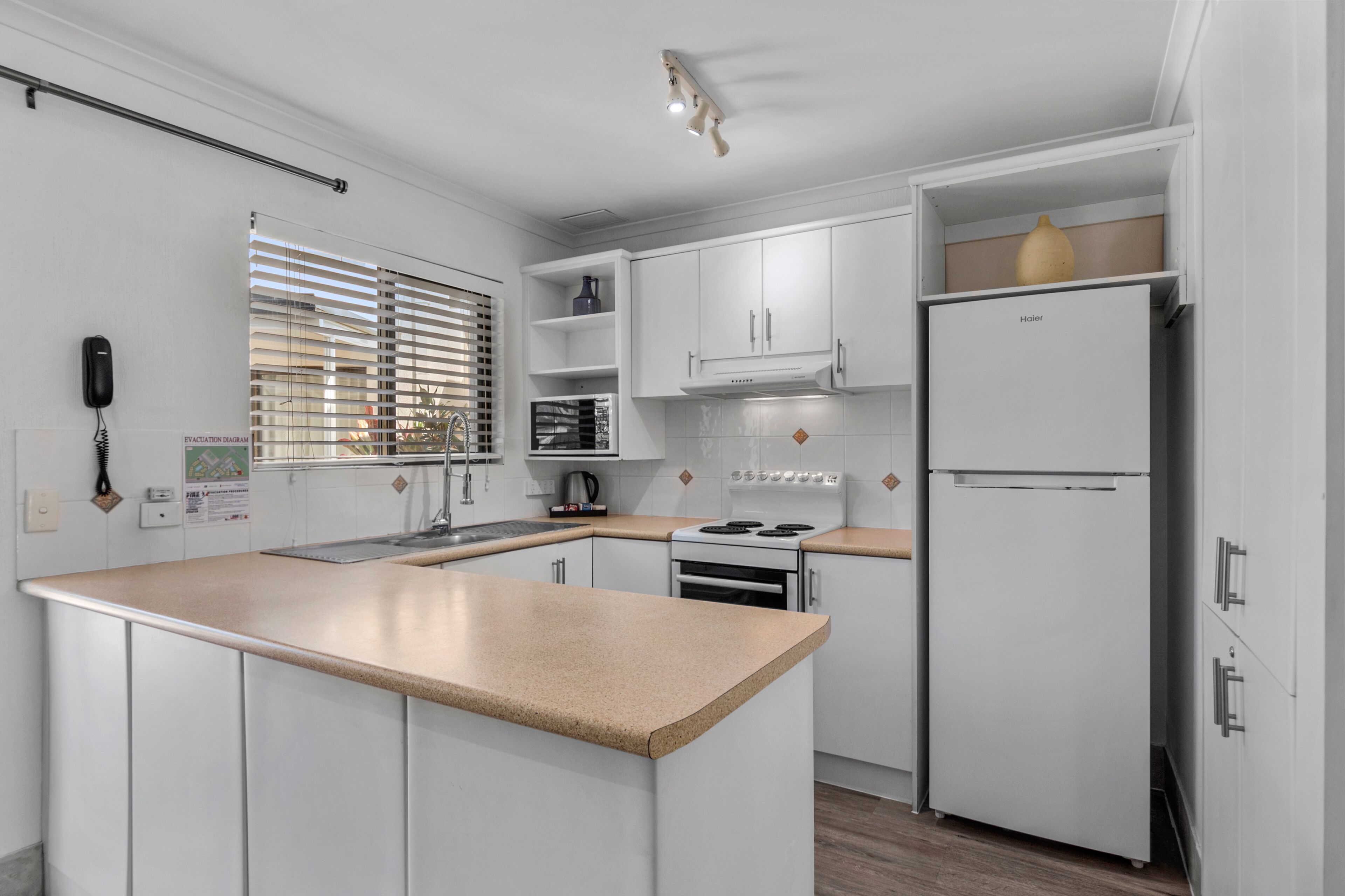A modern kitchen with white cabinetry, a central island, a stove, and a refrigerator.