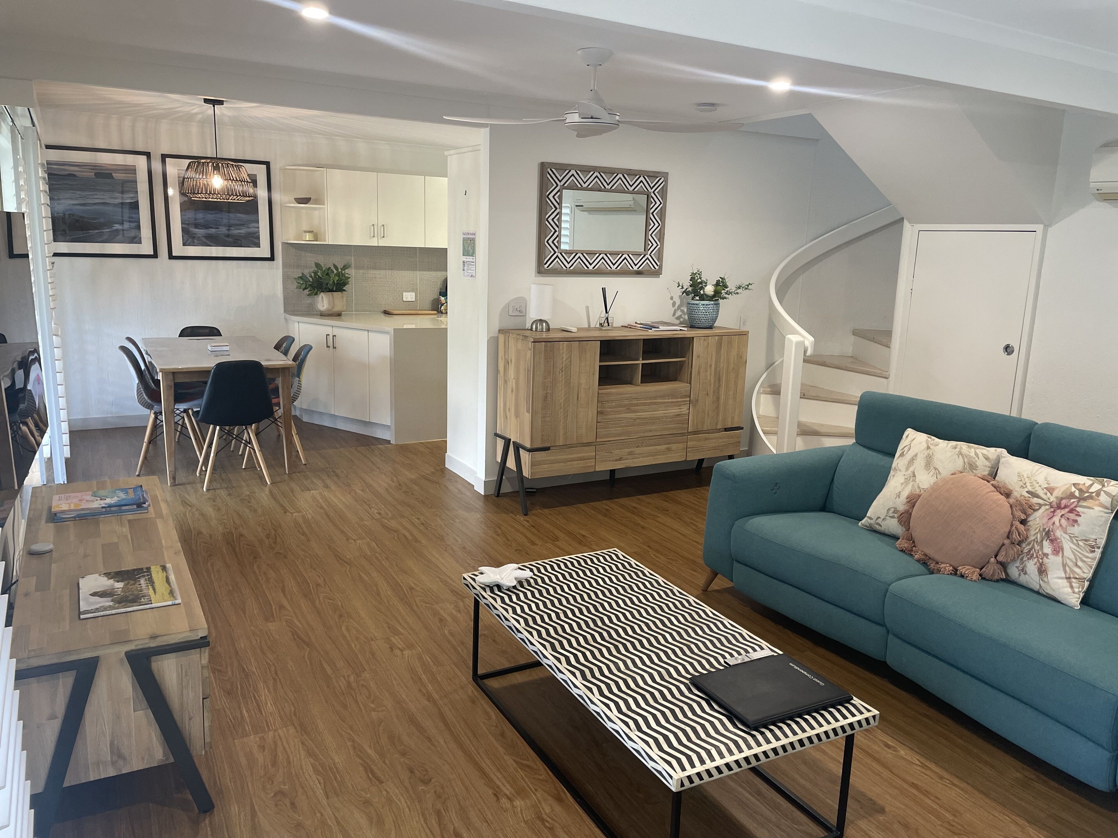 A modern living room with a sofa, a patterned coffee table, and a dining area with chairs and a table.