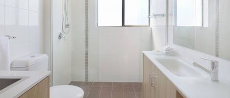 A modern bathroom with a shower, toilet, and sink.
