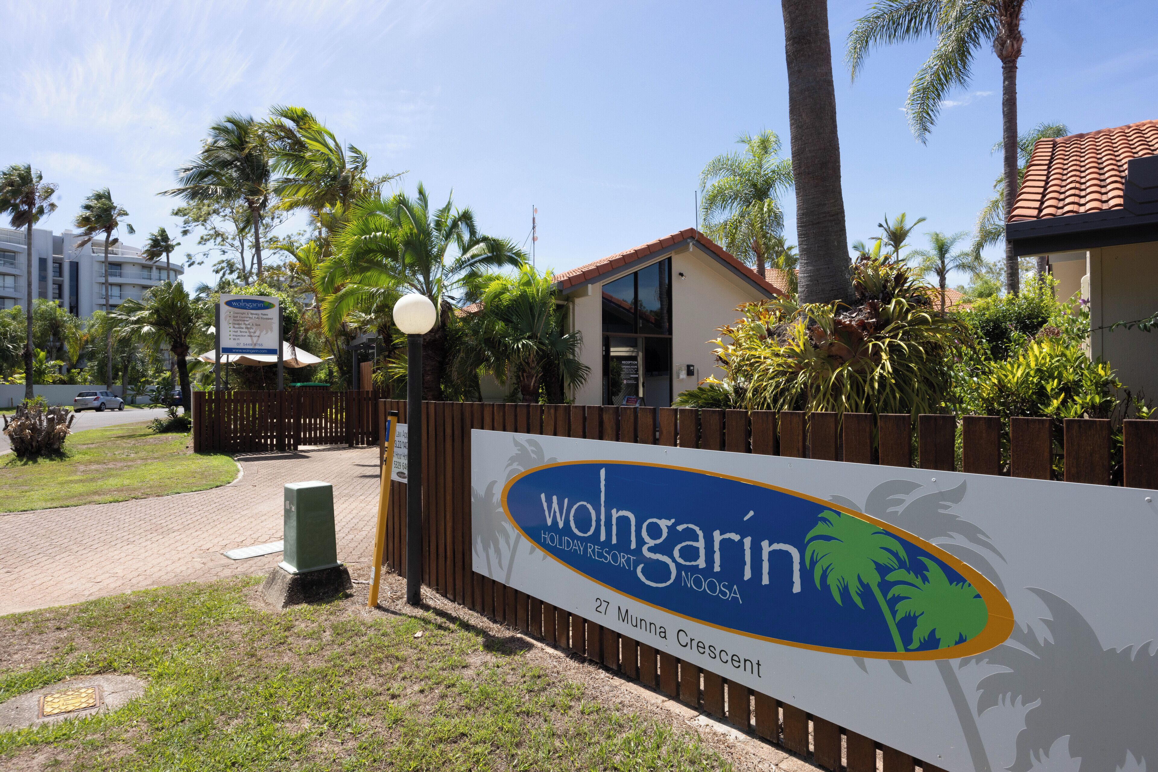 Segnaletica per Wolgarin Holiday Resort Noosa, con palme e cielo sereno sullo sfondo.