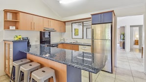 Una cocina moderna con encimera de granito, electrodomésticos de acero inoxidable y armarios de madera.