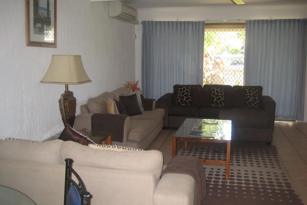 A living room with a beige sofa, a brown sofa, a coffee table, and a lamp.