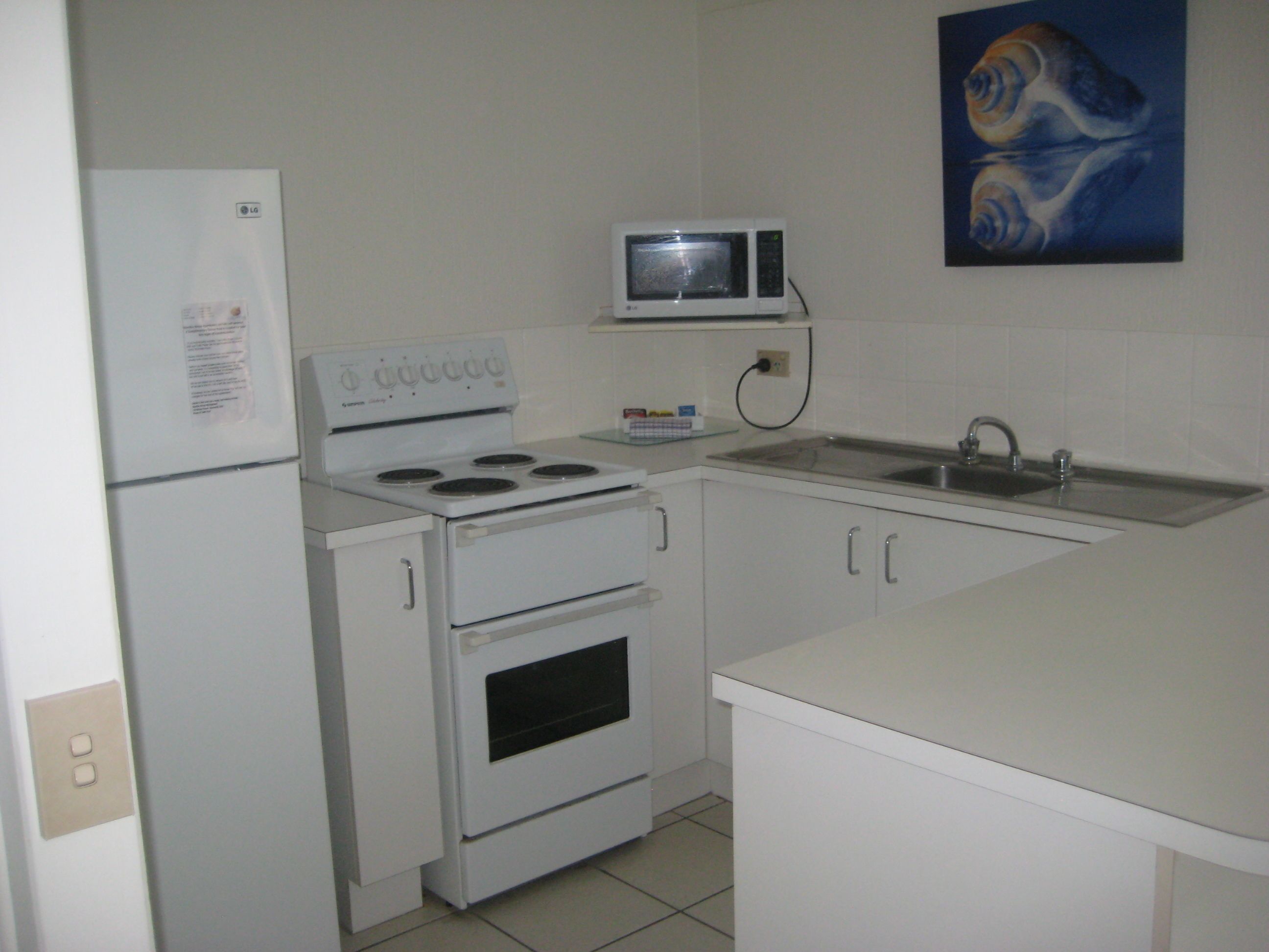 A compact kitchen with a stove, microwave, and sink.