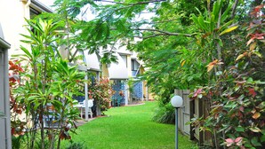 Un jardín bien cuidado con césped, diversas plantas y una valla de madera.