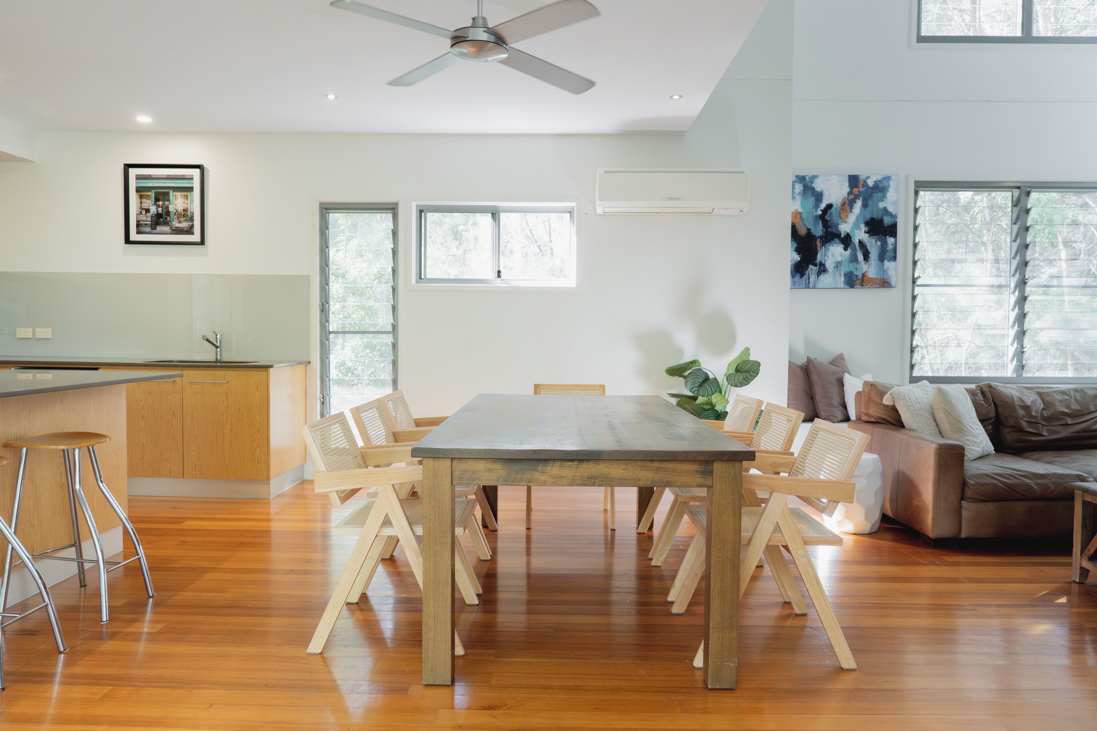 A spacious living area with a wooden dining table, a sofa, and a ceiling fan.