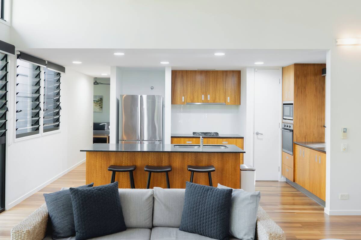 A modern kitchen with stainless steel appliances, wooden cabinets, and a central island with bar stools.