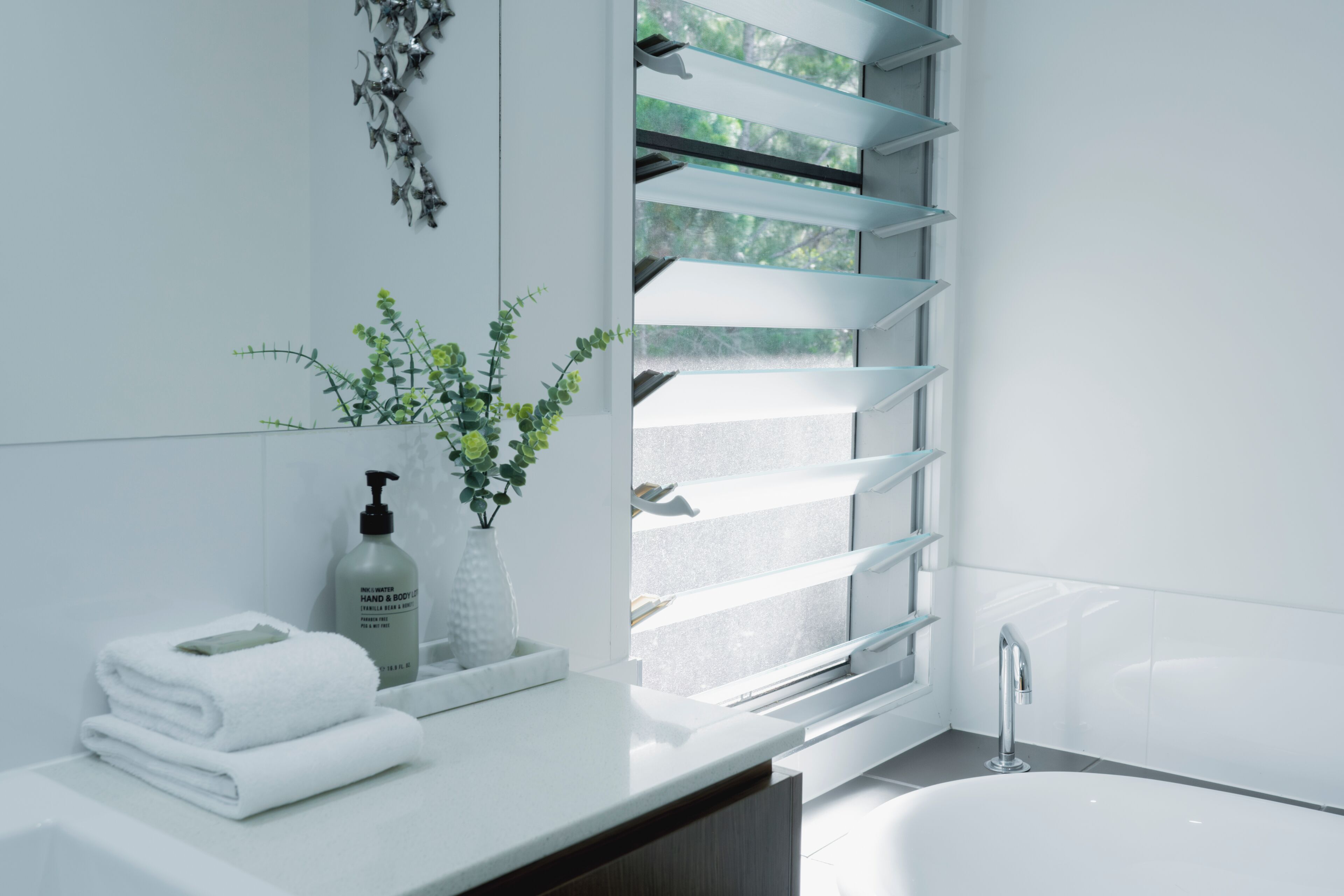 A modern bathroom with a white sink, a glass shower enclosure, and a bathtub.