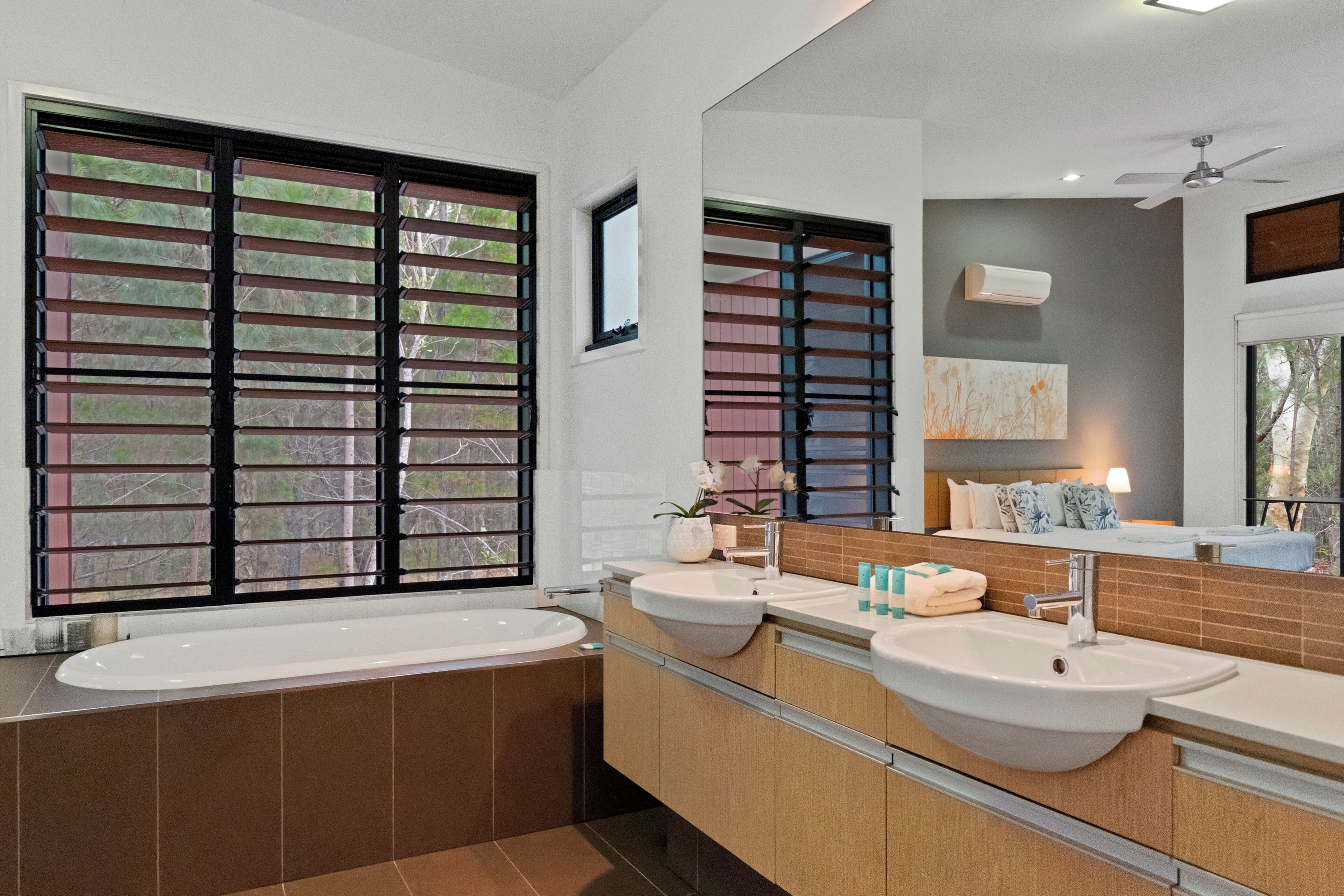 Un bagno moderno con una vasca da bagno ampia, due lavandini e uno specchio grande.