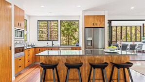 A modern kitchen with wooden cabinets, stainless steel appliances, and a central island with bar stools.