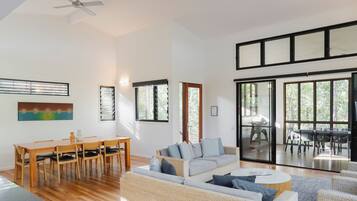 A spacious living area with a dining table, sofas, and a large sliding glass door leading to an outdoor patio.