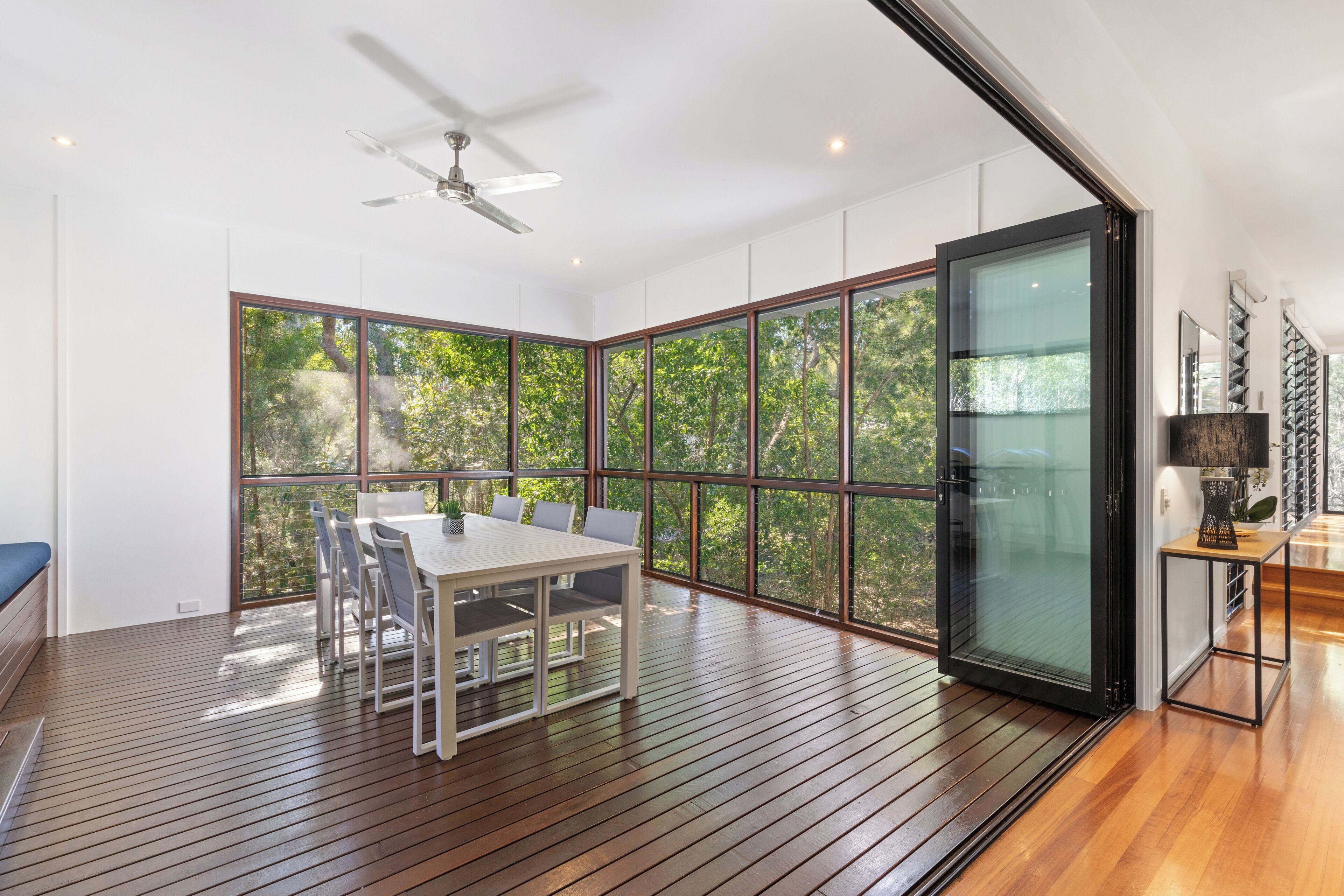 A modern room with a large sliding glass door, a ceiling fan, and a dining table with chairs.