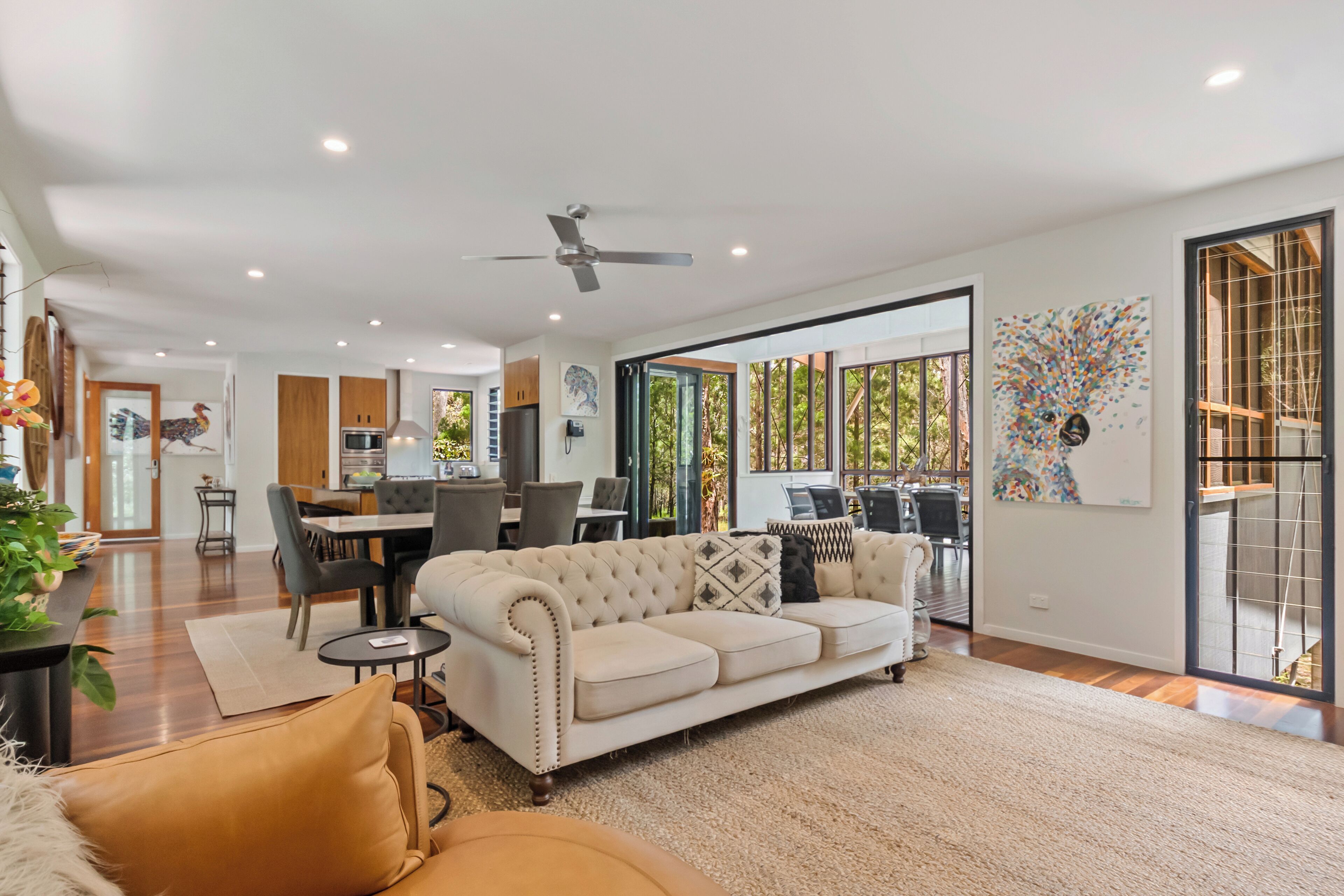 A spacious living area with a large sofa, a dining table, and a kitchen in the background.