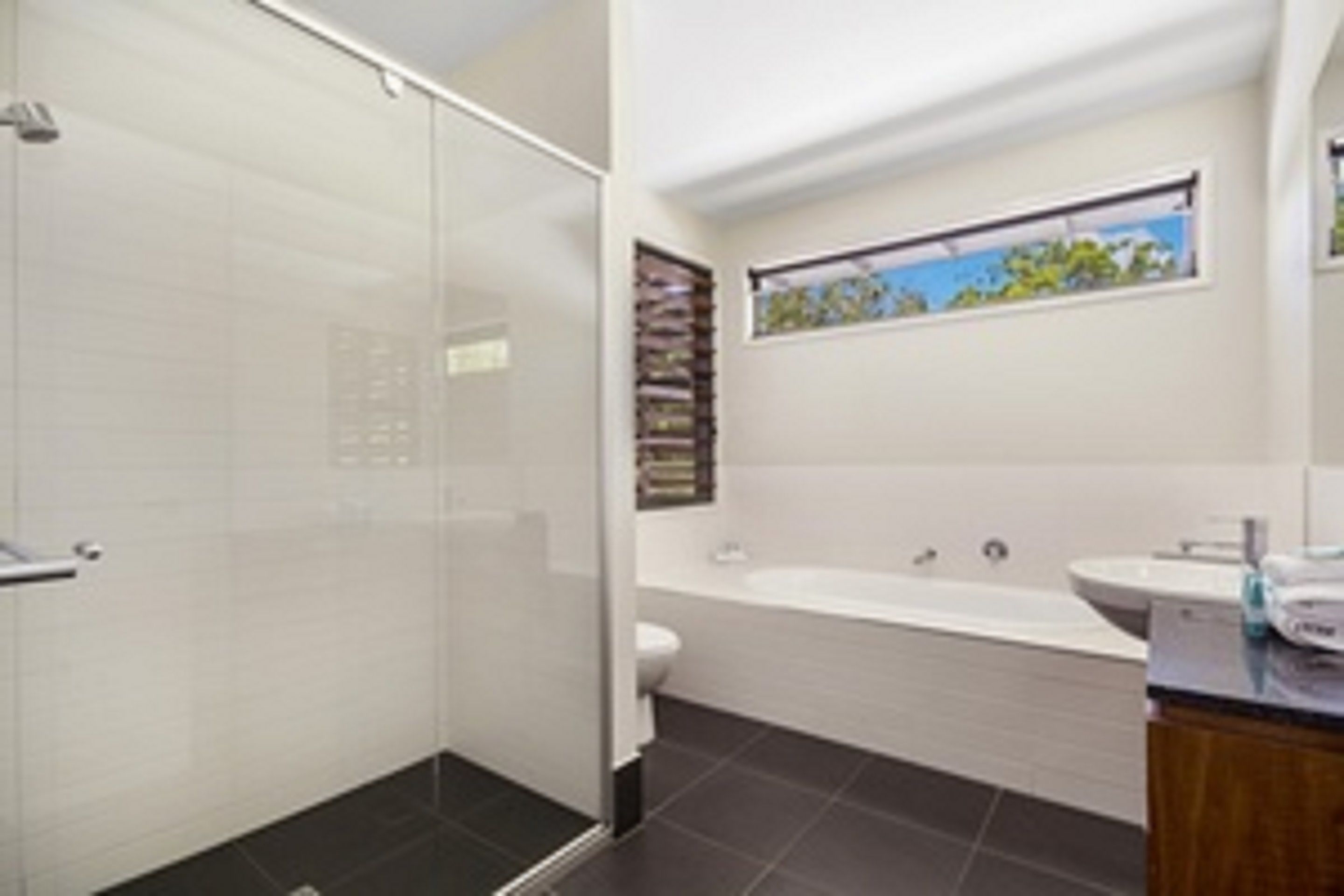 A modern bathroom with a glass shower enclosure, a bathtub, and a sink.