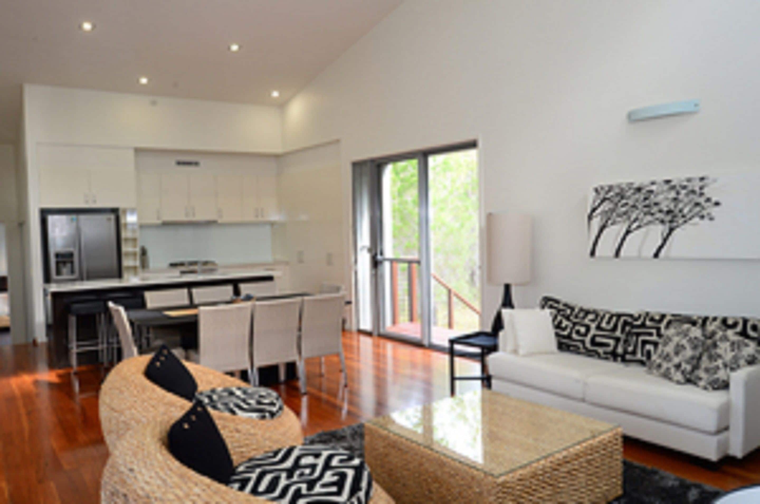 A modern living room with a sofa, a coffee table, and a dining area with chairs and a table.