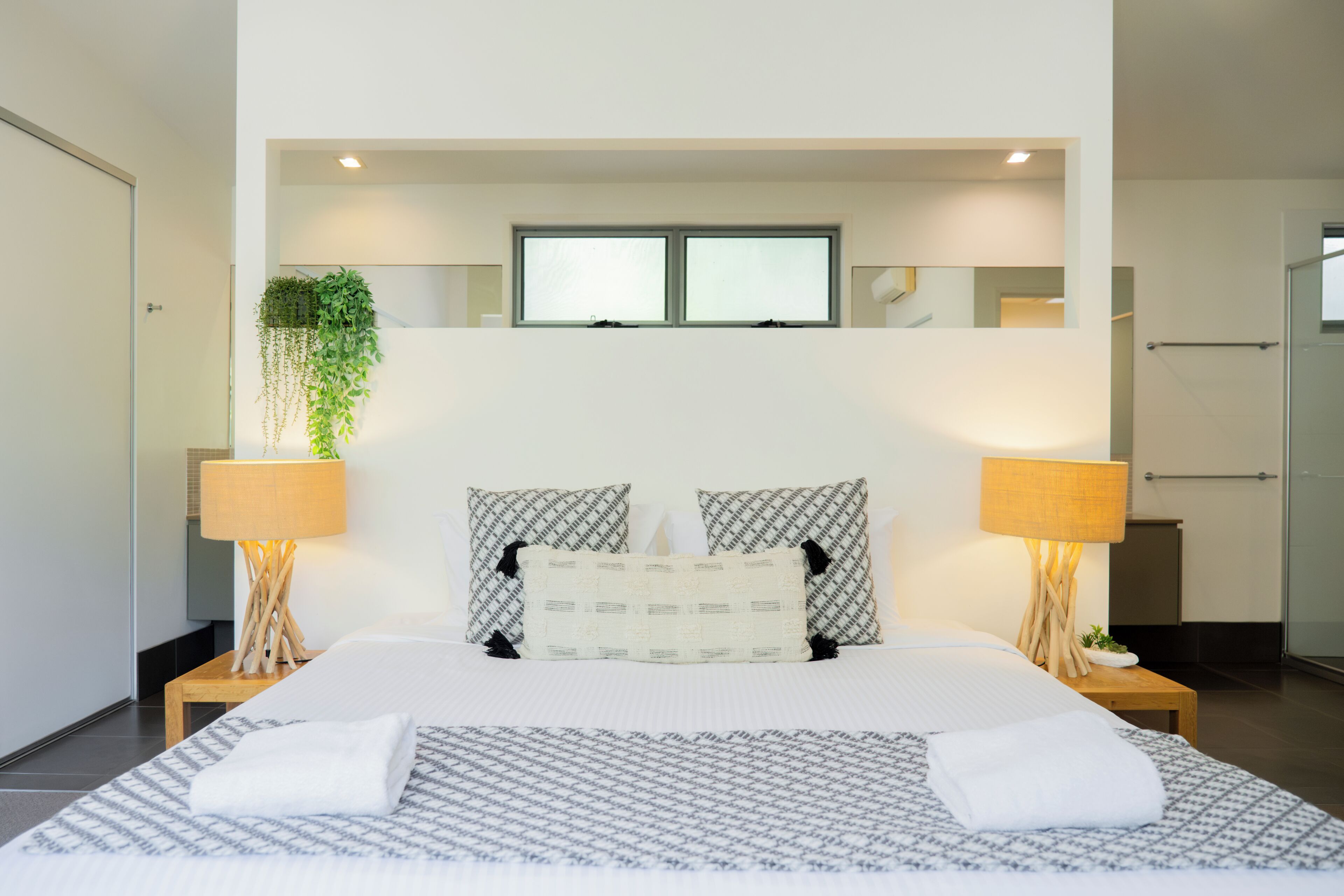 Una habitación de hotel moderna con una cama grande, dos lámparas de noche, un espejo y una ventana.