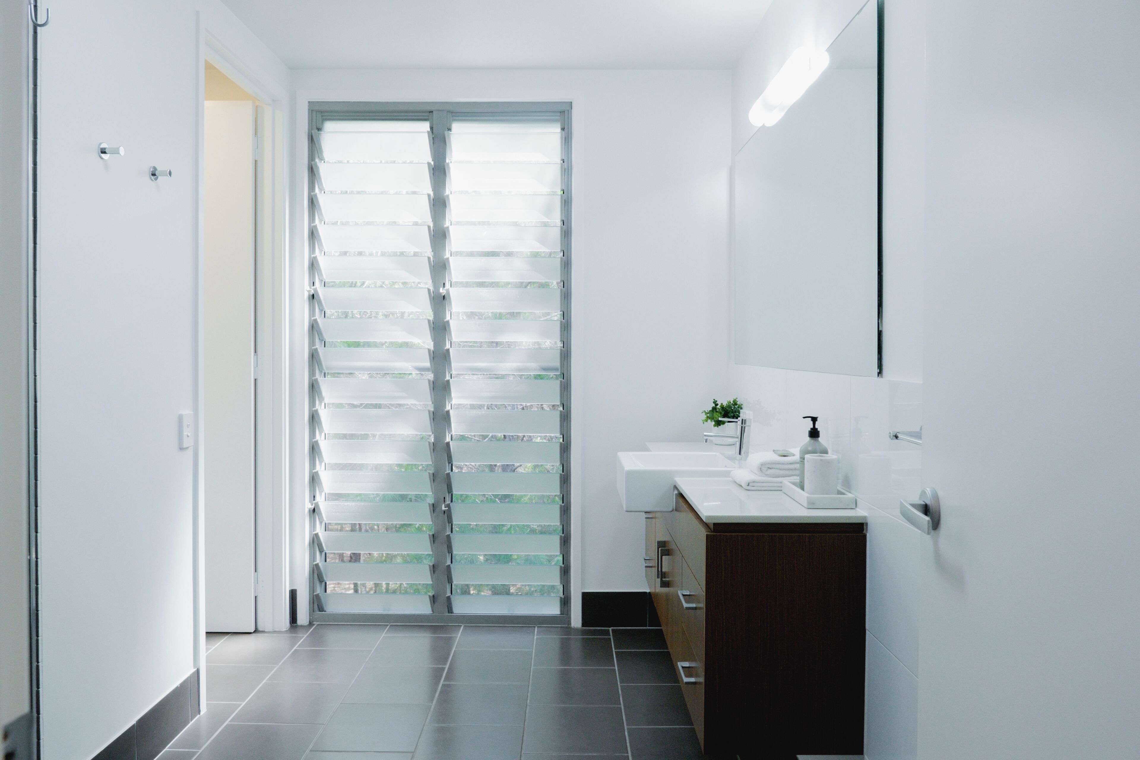A modern bathroom with a glass door, a sink, and a mirror.