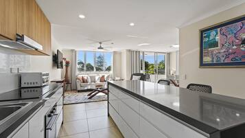 A modern kitchen with a central island, a dining area with a view, and a ceiling fan.