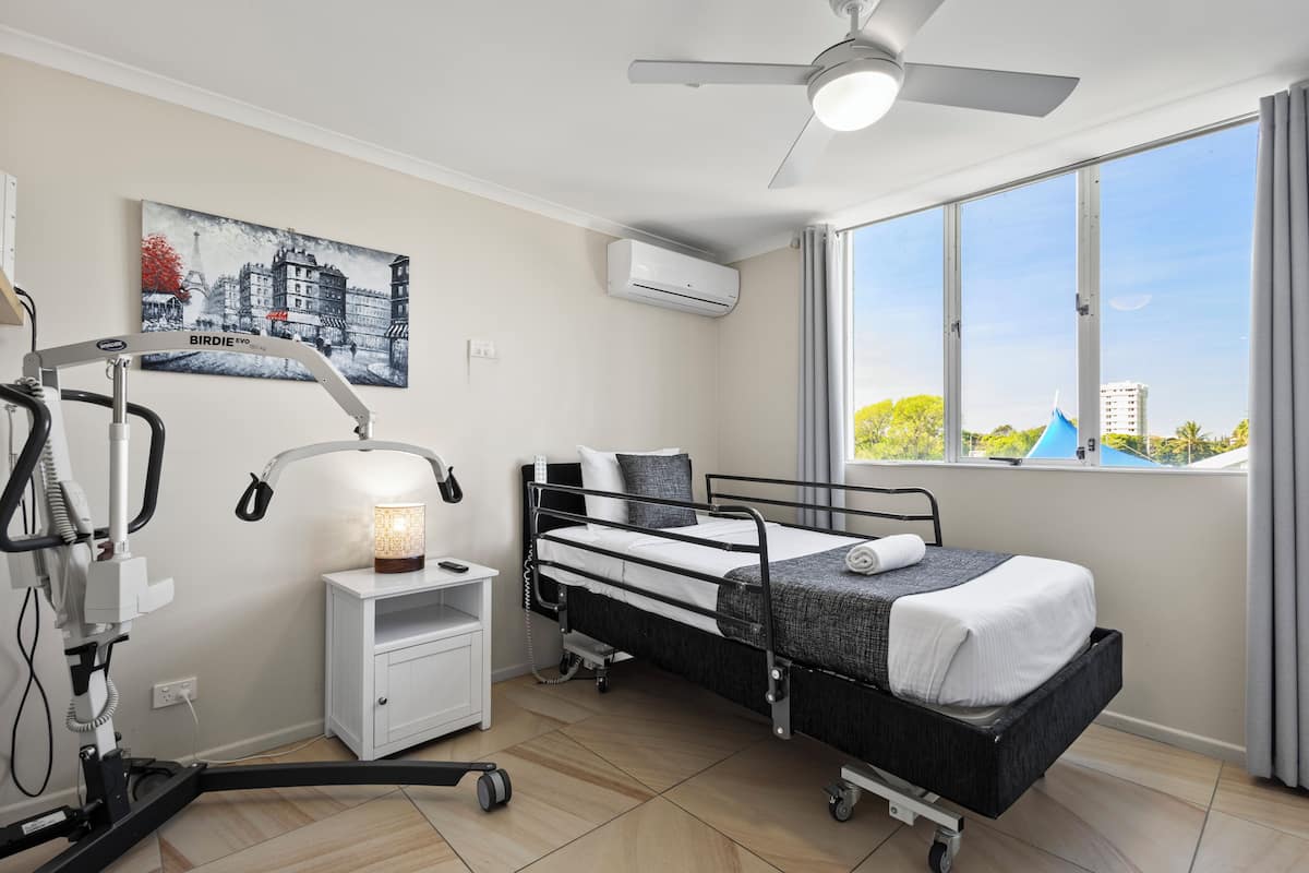 A hospital room with a bed, medical equipment, and a window with a view of buildings.