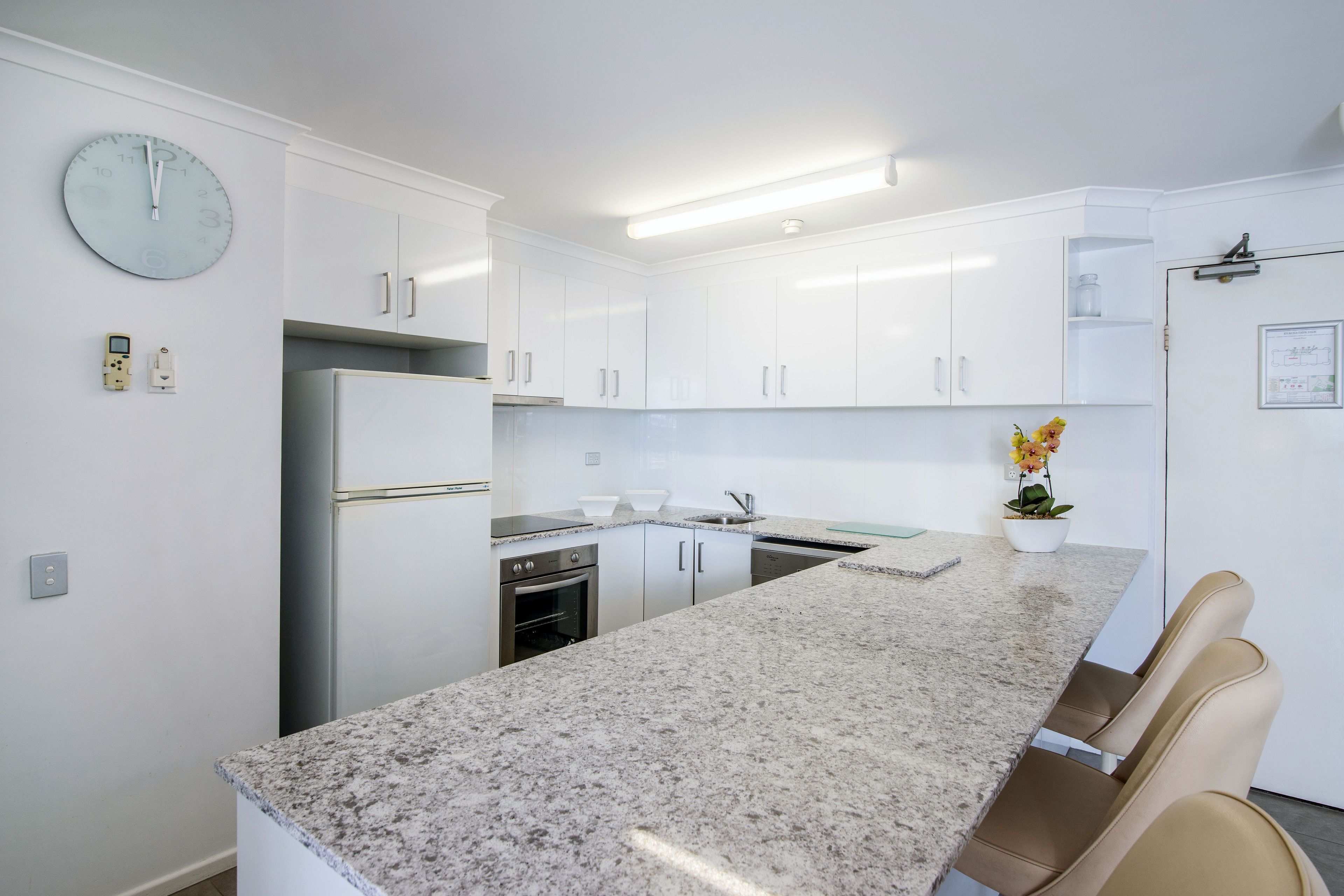 Una cocina moderna con armarios blancos, encimera de granito y horno empotrado.