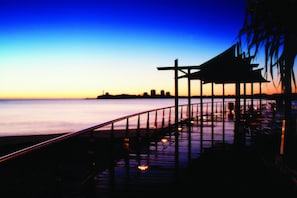 A pier extending into a body of water with a city skyline in the background.